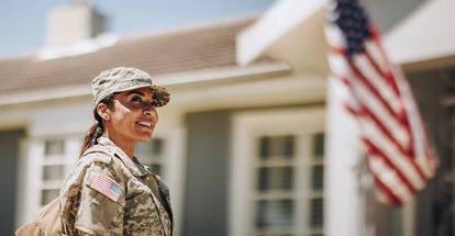 Happy female soldier looking away with a smile while standing outside her house