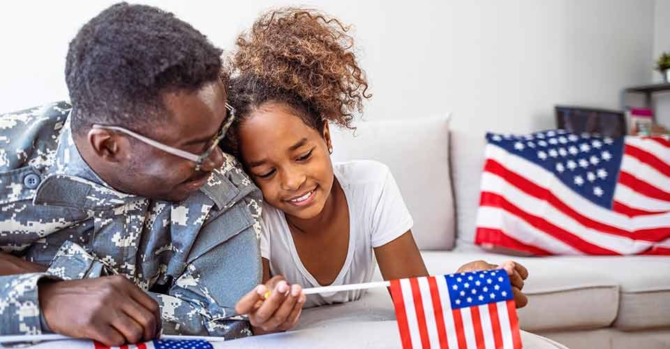 Happy little girl having fun with her military father at home
