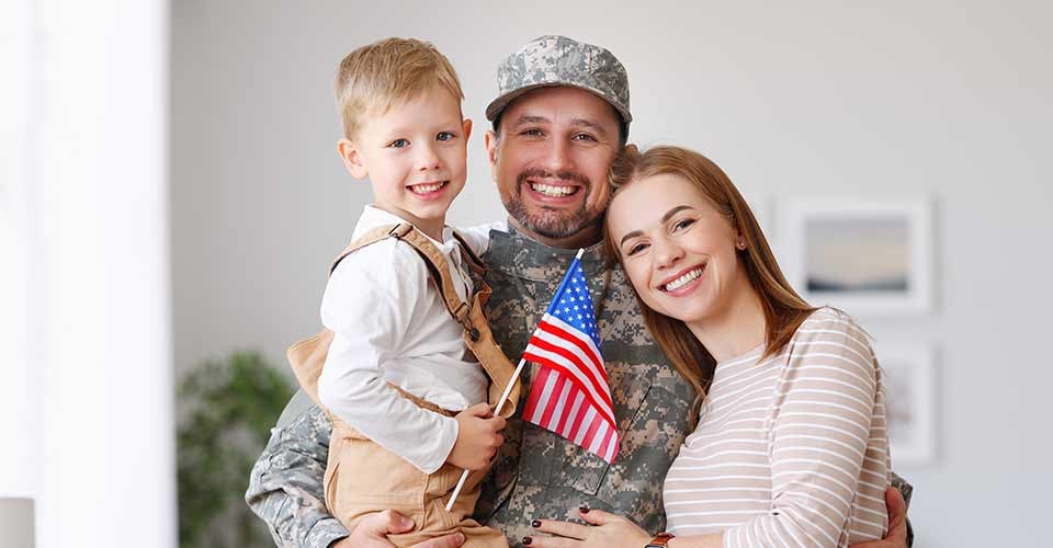 Happy man in military uniform with family in new house