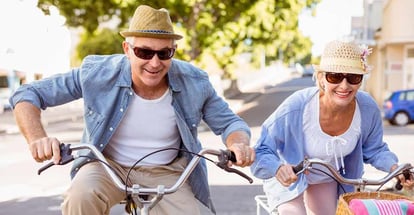 Happy mature couple going for a bike ride in the city on a sunny day
