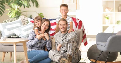 Happy military man with his family sitting on a floor at new home