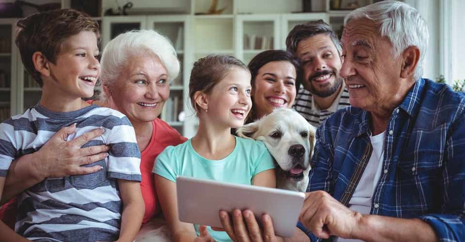 Happy multi generation family using digital tablet in living room at home