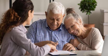 Happy old spouses visiting realtor to buy real estate sign a document