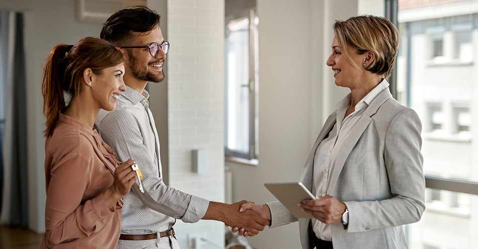 Happy real estate agent and young couple shaking hands after successful agreement