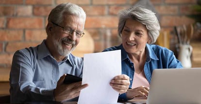 Happy smiling retired couple reading loan paperwork at home