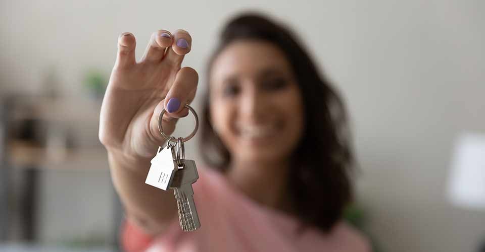 Happy woman showing house keys after moving to new home