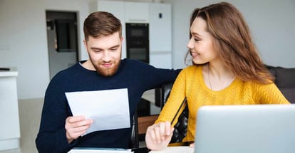 Happy young couple calculating bills at home