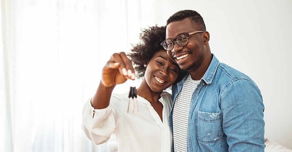 Happy young couple holding key to new home on moving day