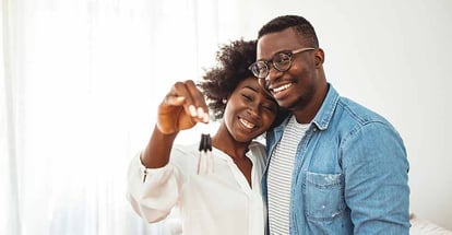 Happy young couple holding key to new home on moving day