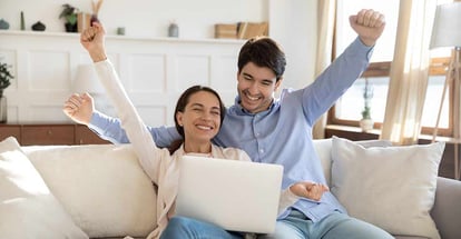 Happy young couple sitting on sofa feeling excited after purchasing new home