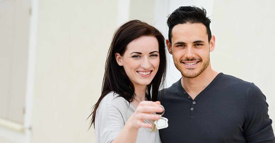 Happy young couple welcome in their new house showing keys