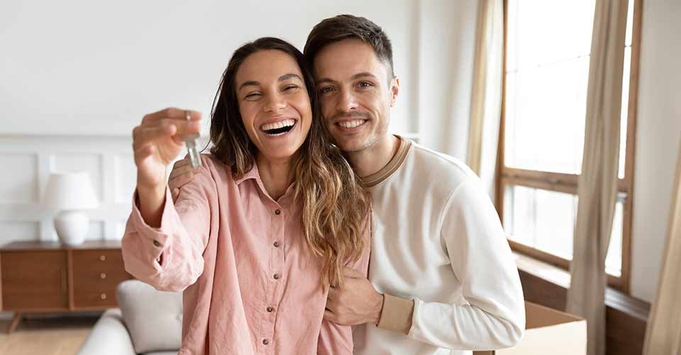Happy young family couple holding key to new home on moving day