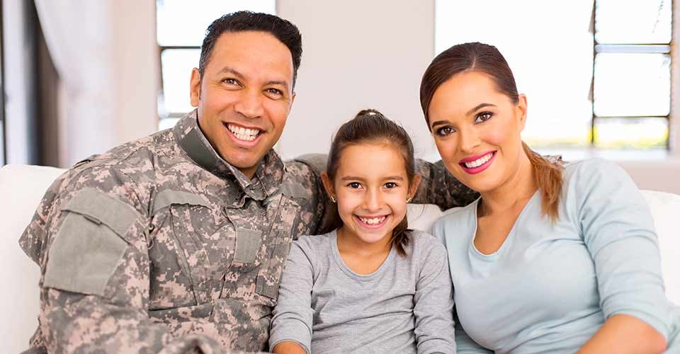 Happy young military family sitting on sofa at new home