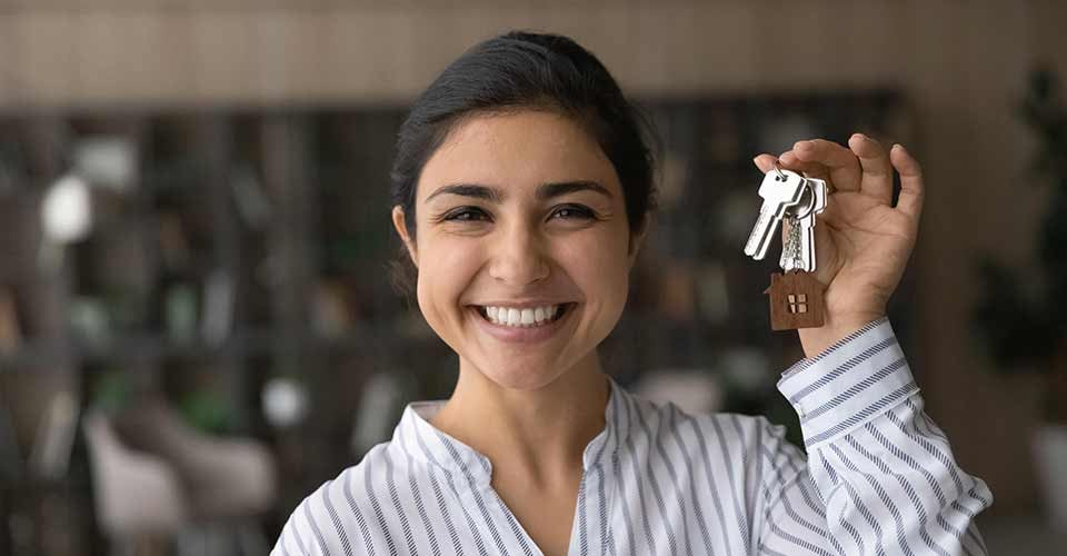 Headshot portrait of smiling young woman show keys to new home