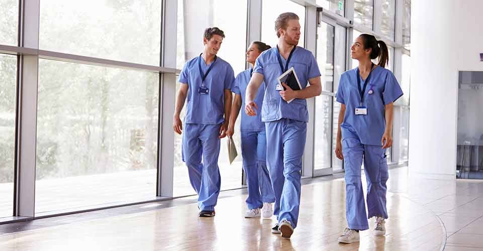 Healthcare workers in scrubs walking in corridor