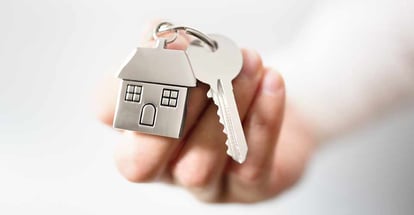 Holding house keys on house shaped keychain after buying a new home