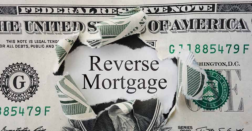 Hole torn in a dollar bill with Reverse Mortgage text