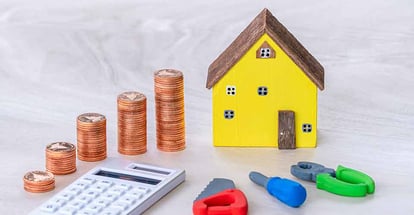 Home model and gold coins with construction equipment for repairing house