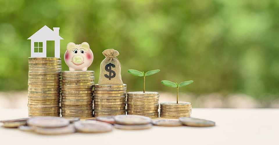 Home model and piggy bank on stacks of rising coins