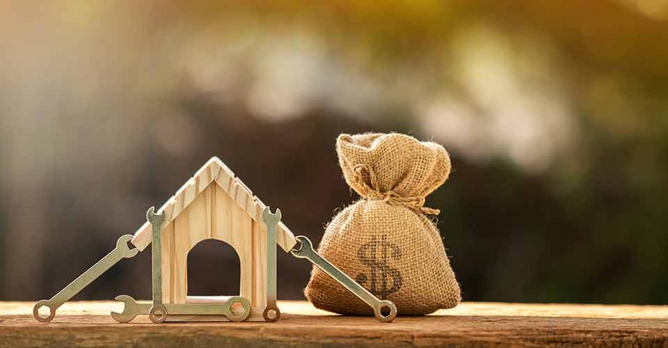 Home model with money bag and construction tools for renovation