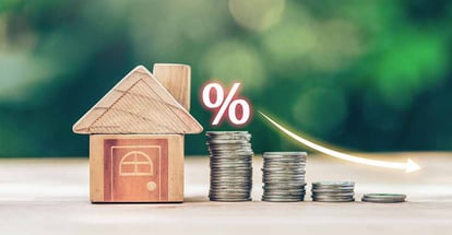 House and coins place on the wood table shows decreasing of mortgage rates