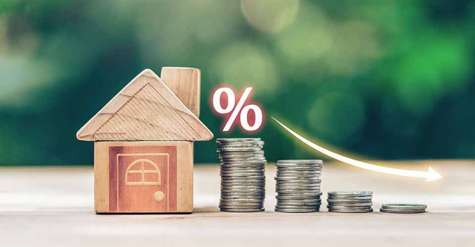 House and coins place on the wood table shows decreasing of mortgage rates