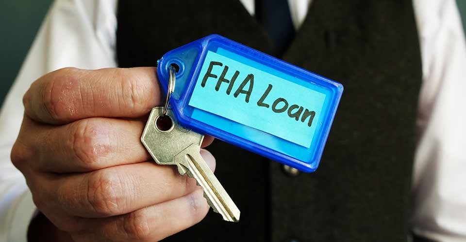 House key with FHA loan sign is in the hands of a man