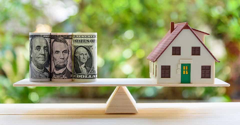 House model and dollar notes on a simple balance scale