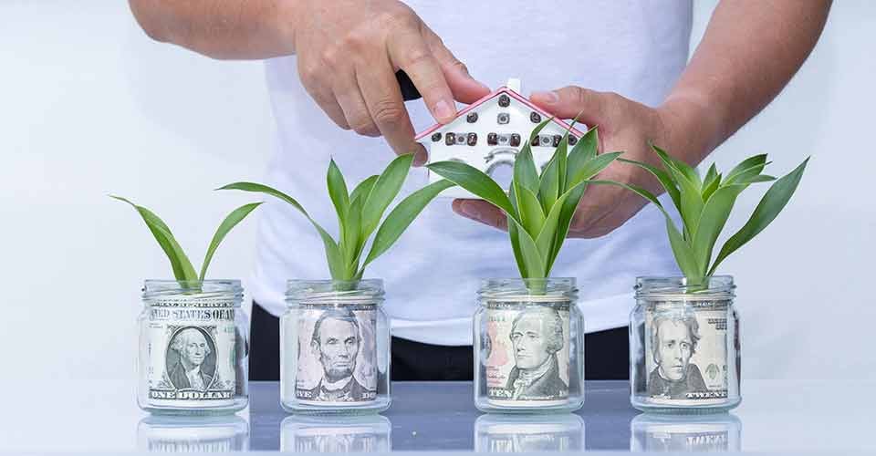 House model on dollar cash stack in glass jar for real estate investment
