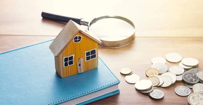 House model on notebook with coins on table