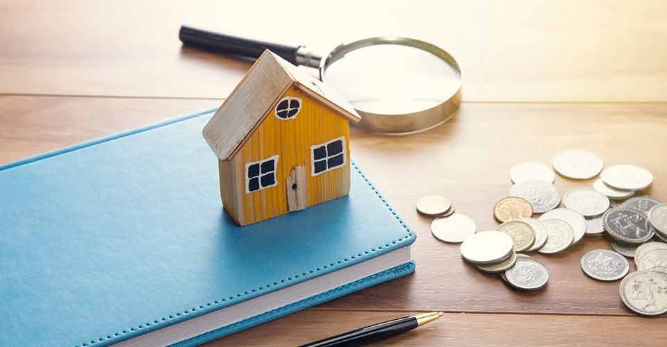 House model on notebook with coins