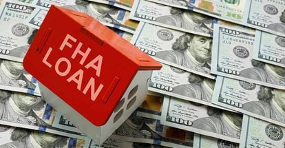 House model with text FHA loan stands on dollar bills