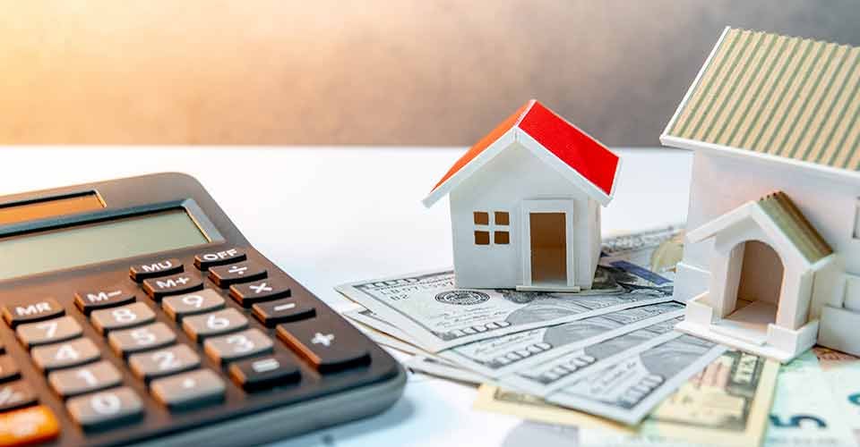 House models on banknotes with calculator on the table