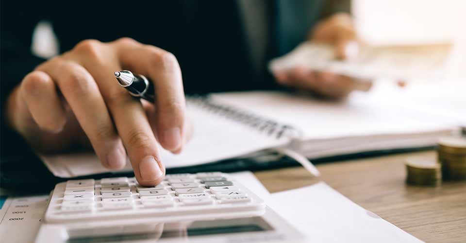 Investor calculating investment costs and holding cash notes in hand