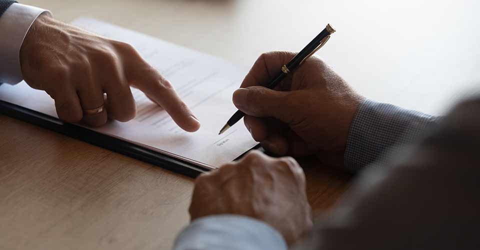 Lawyer pointing at paper for client to sign contract