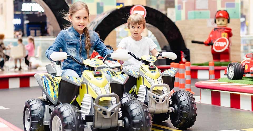 Little kids boy and girl fun riding an small electric cars on sport ground