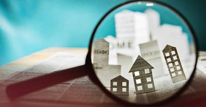 Magnifying glass in front of an open newspaper with paper houses