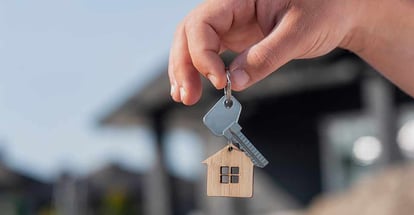 Man holds the keys to house in his hands against the backdrop of residential buildings