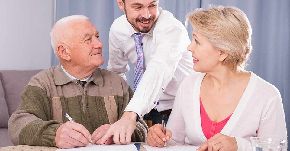 Mature woman and her elderly father signing contract with smiling credit manager at home