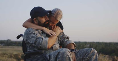 Medium shot of wife hugging wheelchaired soldier husband