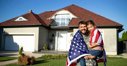 Military father holding his lovely daughter in front of their new house