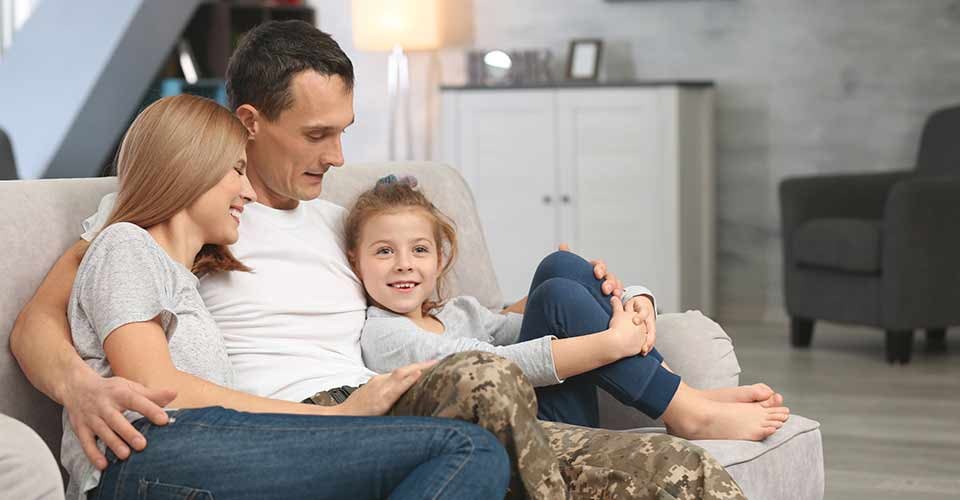 Military father with his family on sofa at new home