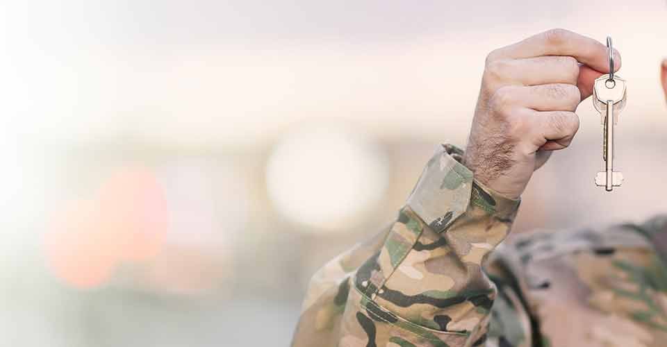 Military man in uniform holding a new home keys