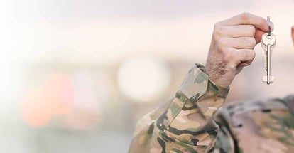 Military man in uniform holding a new home keys