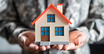 Military officer holding model house on hand