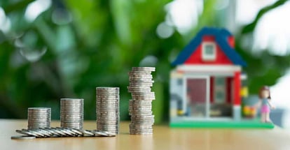Mini wooden house and row of coin stacks for home purchase