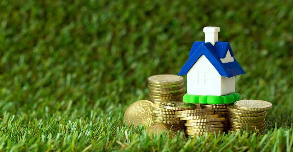 Miniature house with stack of gold coins to buy investment property