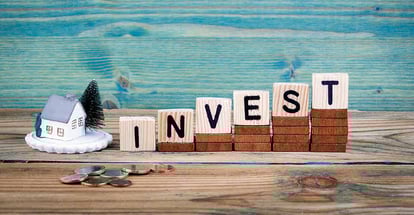 Miniature model house and invest text on wooden cube