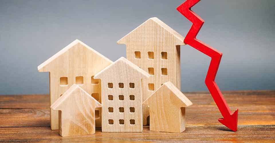 Miniature wooden houses and a red arrow down for mortgage rates