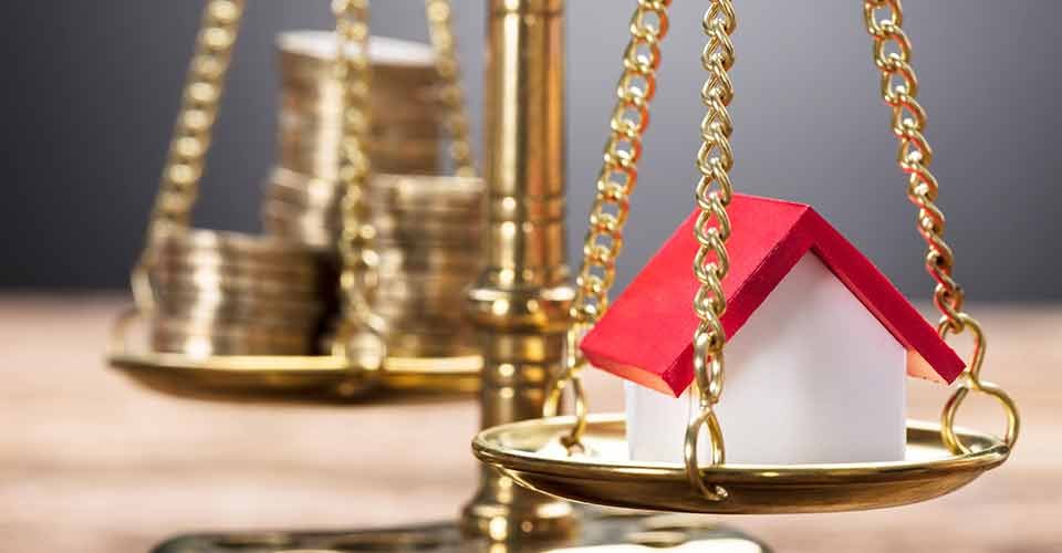 Model home and coins on weighing scale